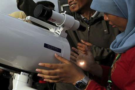 Una joven ve el eclipse reflejado en su mano através de un telescopio en Indonesia