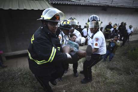 AP Foto/Oliver de Ros / AP Bomberos cargan a una mujer que se desmayó fuera de una correccional de jóvenes y adultos, el Centro Correccional Etapa II, en donde se presentó un motín y un incendio en San José Pinula, Guatemala, el domingo 19 de marzo de 2017. Al menos un encargado de monitoreo del centro falleció durante la revuelta, indicó el portavoz de la policía Pablo Castillo.