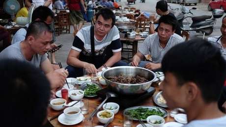 Homens comendo em festival que vende carnes de cachorro na China