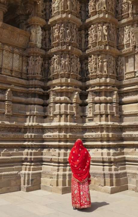 Uma mulher de burca admira esculturas eróticas em um templo