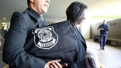 Agente carrega bolsa com emblema da Polícia Federal