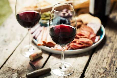 Duas taÃ§as de vinho tinto e um prato com frios