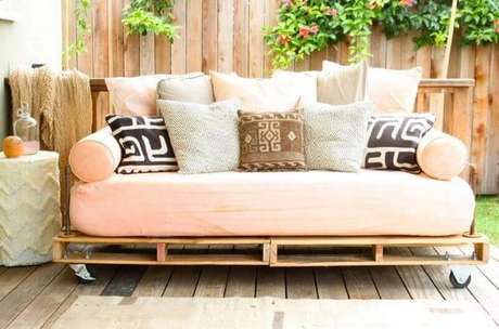 6. Lindo sofá de pallet em tom de rosa e com muitas almofadas compondo a decoração.