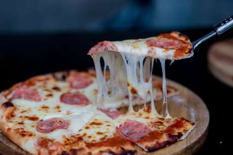 Fatia de pizza de calabresa sendo retirada