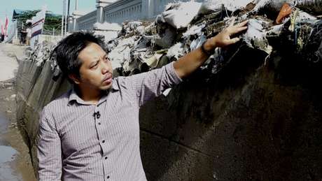 Heri Andreas mostra um dique que foi construído para impedir a água do mar de inundar as casas quando chove