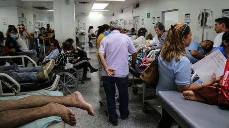 Pacientes ficam aglomerados em macas ou cadeiras de rodas ao longo do corredor, porque faltam leitos