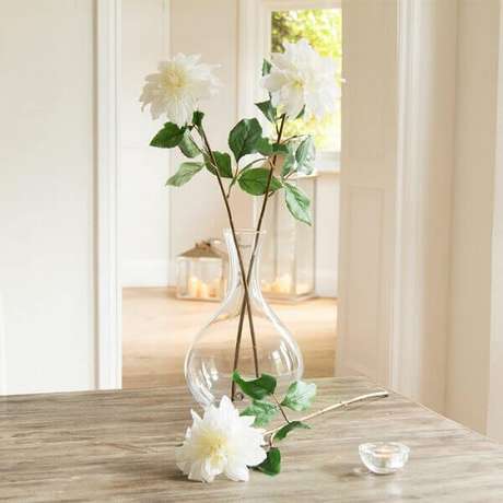 23- As três flores artificiais brancas em um vaso alto de vidro transparente cria uma atmosfera de leveza e requinte ao ambiente. Fonte: Peony 23- As três flores artificiais brancas em um vaso alto de vidro transparente cria uma atmosfera de leveza e requinte ao ambiente. Fonte: Peony