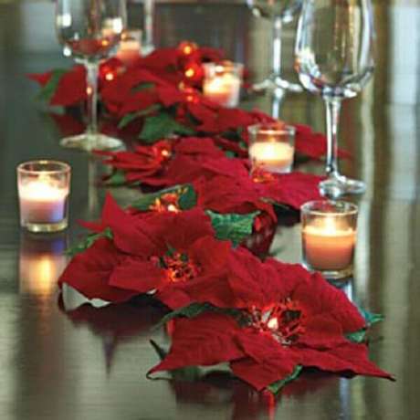 34- O centro de mesa foi elaborado com diversas velas e muitos arranjos de flor de natal. Fonte: Paula Lorentz 34- O centro de mesa foi elaborado com diversas velas e muitos arranjos de flor de natal. Fonte: Paula Lorentz