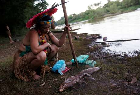 IndÃ­gena da tribo PataxÃ³ HÃ£-hÃ£-HÃ£e observa peixe morto na margem do rio Paraopeba