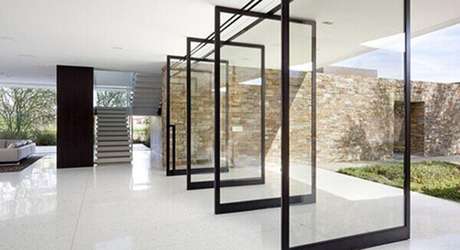 56- Os modelos de portas pivotantes de vidro com caixilhos de alumínio preto decoram a sala em estilo contemporâneo. Fonte: Design Coolture