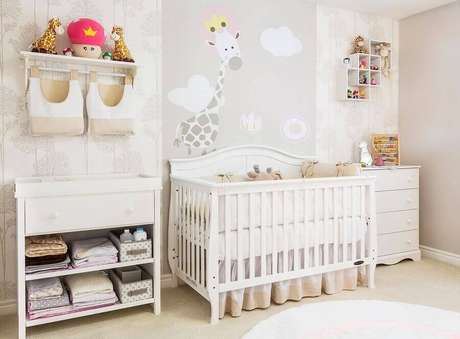 58. Prateleira para quarto de bebê todo branco decorado com adesivo de girafa na parede – Foto: Andrea Bento