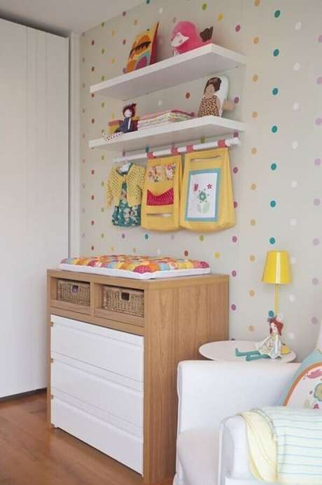 68. Decoração com prateleira para quarto de bebê com cômoda de madeira e adesivos de bolinhas coloridas na parede cinza – Foto: Vamos Mamães