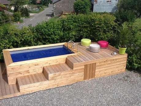 38. Caso não tenha espaço para espreguiçadeiras, use puffs coloridos para decorar sua piscina de paletes. Fica incrível!