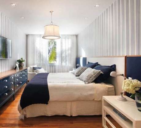 62. Quarto de casal decorado com cômoda azul comprida com tampo de madeira – Foto: Paola Ribeiro