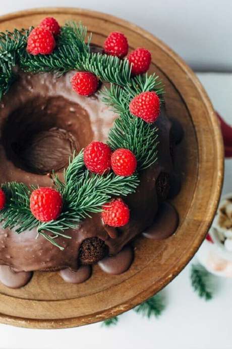 45. Decoração tradicional de bolo de Natal simples com cobertura de chocolate, raminhos verdes e frutas vermelhas – Foto: Vamos Receber