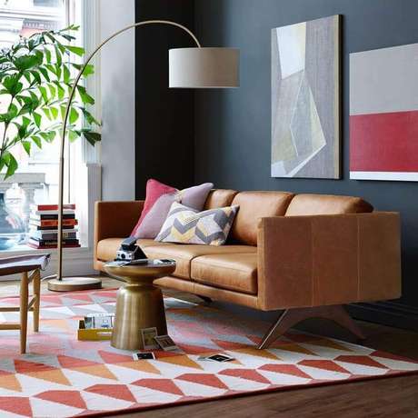 51. Modelo de sofá de couro com design moderno para sala com parede preta e tapete colorido – Foto: Assetproject 51. Modelo de sofá de couro com design moderno para sala com parede preta e tapete colorido – Foto: Assetproject