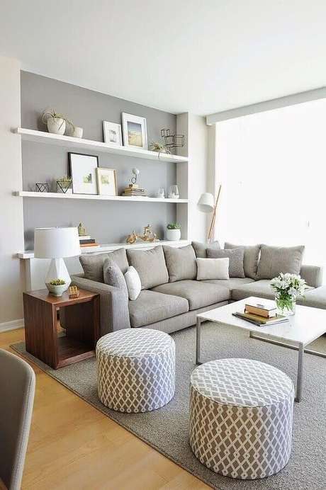74. Sofá de canto para sala cinza decorada com prateleiras brancas e puffs redondos – Foto: Infinity Design 74. Sofá de canto para sala cinza decorada com prateleiras brancas e puffs redondos – Foto: Infinity Design