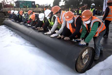 Operários da construção civil instalam revestimento à prova de umidade