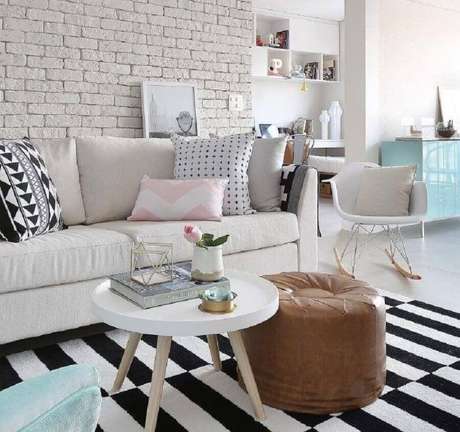 56. Almofadas para sofá branco para sala decorada com tapete listrado preto e branco e puff redondo de couro – Foto: Priscilla Dattilio