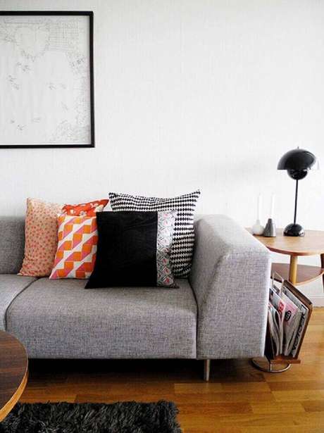 14. Almofadas para sofá cinza em tons fortes como laranja garantem mais alegria à decoração.