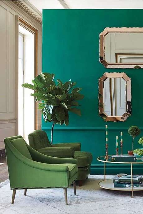 7. Parede verde para decoração de sala sofisticada com espelhos e poltronas verdes – Foto: Novero Homes