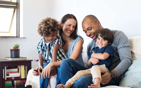 Casal multiracial, com dois filhos, sentados em um sofá