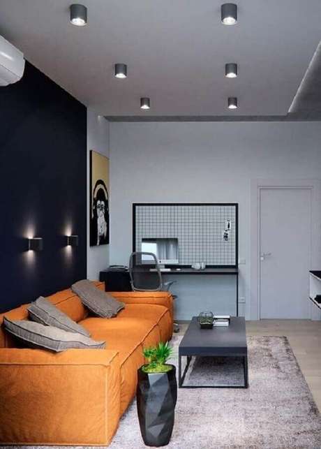 7. O sofá laranja deu um ar descontraído para a decoração da sala com parede preta – Foto: Revista VD