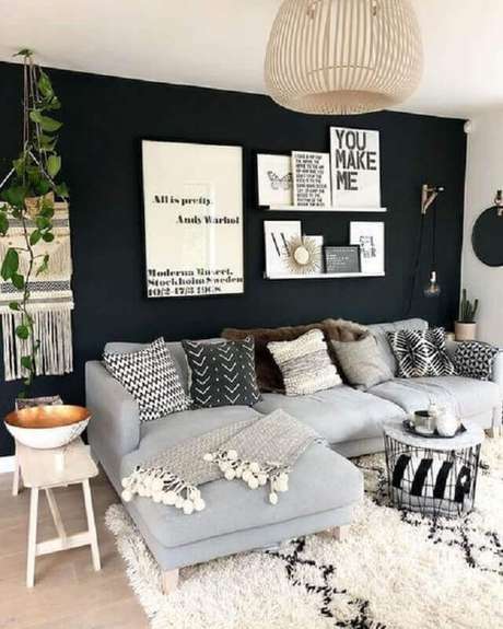 48. Sala com parede preta decorada com quadros e várias almofadas para sofá cinza com chaise – Foto: Pinterest