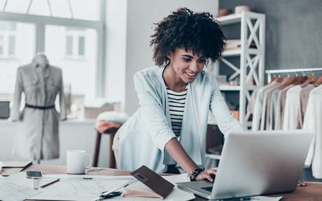 Mulher negra mexendo no computador em uma loja de roupa