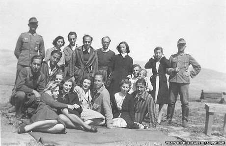 Isaac Jacob Menache (em pé, o terceiro a partir da esquerda) no campo de trabalho forçado do aeroporto militar de Atenas, sob ocupação alemã, 1944 Isaac Jacob Menache (em pé, o terceiro a partir da esquerda) no campo de trabalho forçado do aeroporto militar de Atenas, sob ocupação alemã, 1944