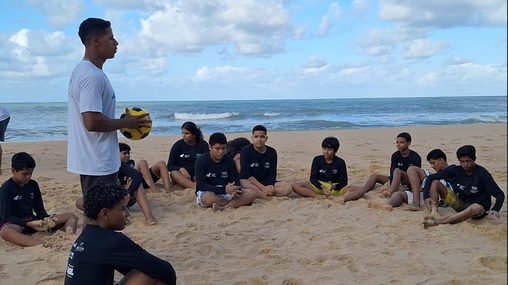 Instrutor conversa com crianças antes de práticas esportivas na praia em Baía Formosa (RN).