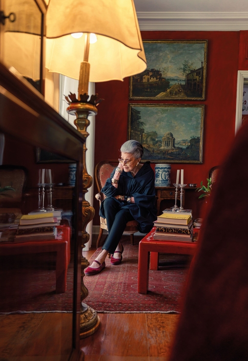 Constanza cercada por livros, quadros e cerâmicas que compõem a decoração de sua casa