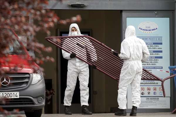 Juan Medina / Reuters Homens trabalham para isolar a região de Madri, na Espanha