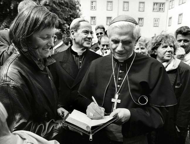 Em 1994, ratzinger já gozava de fama entre católicos. Nesta imagem, feita em junho, ele autografa uma publcação no aniversário de 1240 anos da cidade alemã de Fulda