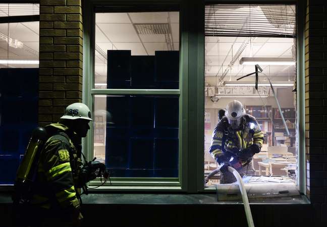 <p>Bombeiros combatem as chamas em sala de escola incendiada em Tensta, no subúrbio de Estocolmo</p>