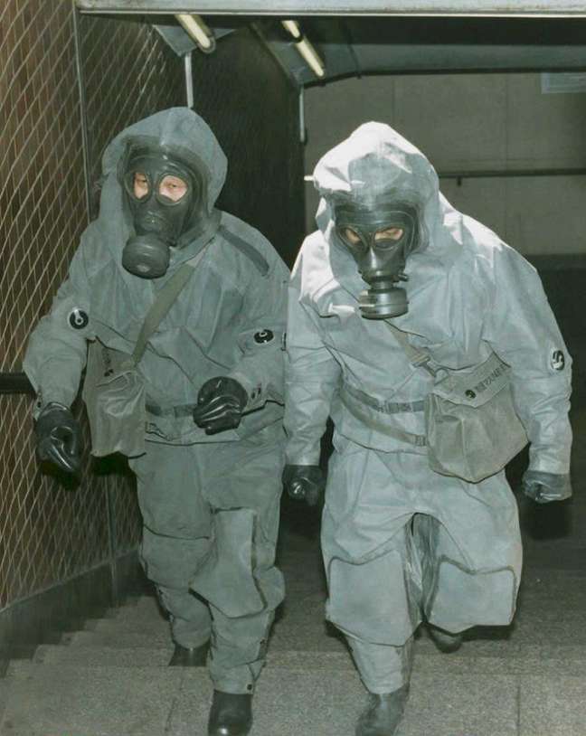 <p>Policiais com trajes protetores sobem escadas de metrô de Tóquio após o ataque com gás sarin</p>