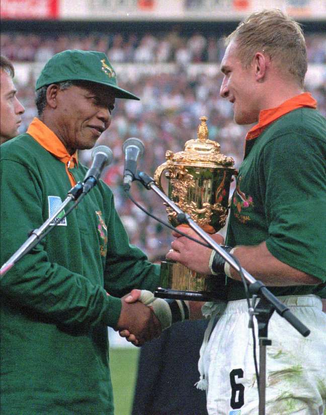 Mandela entrega troféu da Copa do Mundo de Rúgbi para o capitão sul-africano Francios Pienaar (dir.), em 24 de junho de 1995