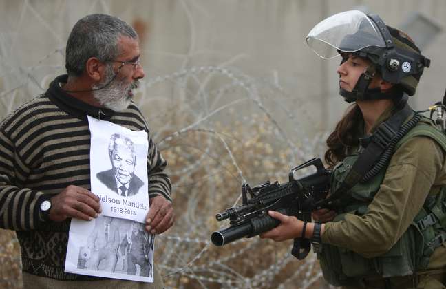 Palestino olha para policial israelense durante ato em homenagem a Mandela, perto de Ramallah