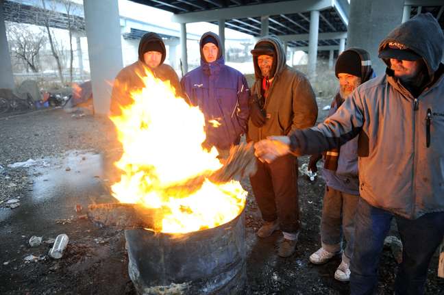 Moradores de rua de Knoxville enfrentam as temperaturas negativas e a expectativa de uma pesada frente fria com lareira improvisada em tonel