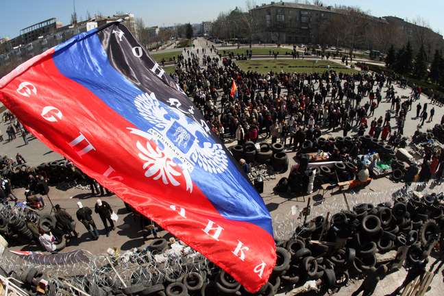 <p>A bandeira da chamada "República Federativa Donetsk" foi colocada em cima de uma barricada, e uma multidão de militantes pró-Rússia se reuniu em frente ao prédio da administração regional de Donetsk, nesta terça-feira, 8 de abril</p>