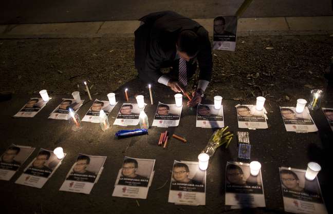 <p>Um homem acende velas com cartazes de fotos do chileno Daniel Zamudio escrito "Homofobia mata", em frente à embaixada do Chile, em Buenos Aires, em março de 2012. Zamudio, um jovem gay, foi atacado em um parque em Santiago, Chile, e morreu após ser espancado por uma hora e sofrido queimaduras de cigarro </p>