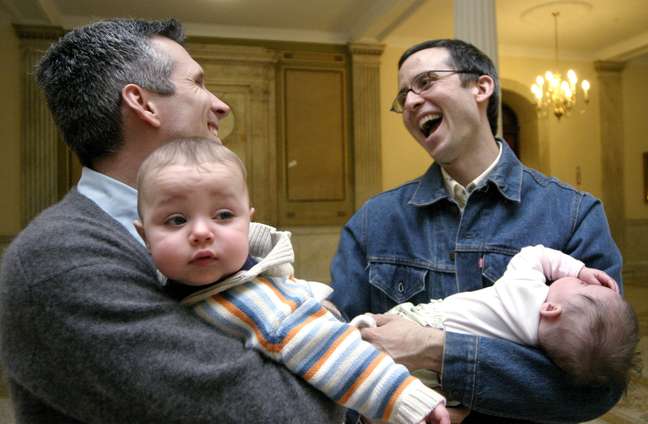 <p>Corey Clifford, à esquerda, e Christian Schlesinger, seguram filhos adotivos e conversam, durante um comício, em fevereiro de 2004, na Assembléia, em Boston, que discutia a proposta para proibir o casamento homossexual</p>