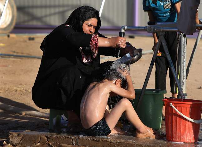  22 de junho - mulher iraquiana banha seu filho em um acampamento para deslocados iraquianos que fugiram de Mossul e outras cidades tomadas pelos insurgentes do Estados Islâmico e do Levante