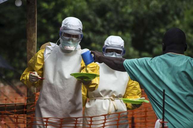 <p>Equipe do Médicos Sem Fronteiras serve refeições a pacientes mantidos em uma área de isolamento em um centro de tratamento de ebola em Kailahun, Serra Leoa, em 20 de julho</p>