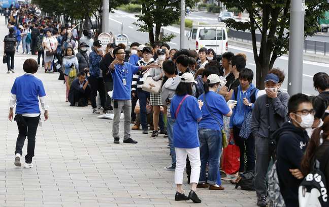 Funcionários da Apple tentam organizar a fila em frente a loja da Apple em Tóquio, Japão 