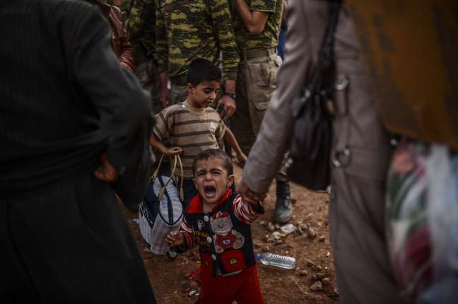 Criança curda chora ao chegar na Turquia após fugir com família de confrontos no território sírio