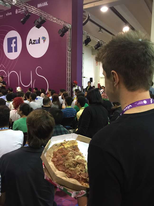 <p>Rapaz come pizza comprada fora do evento durante passagem no Palco Vênus</p>