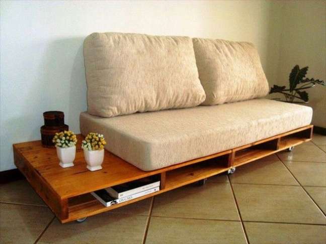 O suporte do sofá é feito com pallets, que apresentam nichos para guardar revistas