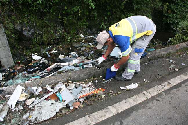 Funcionário da rodovia recolhe pertences das vítimas do acidente