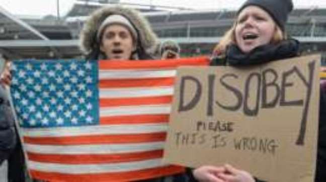 "Desobedeçam, por favor. Isso é errado", diz o cartaz de uma manifestante em Nova York